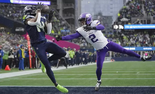 Seattle Seahawks wide receiver DK Metcalf (14) catches a 25-yard touchdown pass ahead of Minnesota Vikings cornerback Stephon Gilmore (2) during the first half of an NFL football game, Sunday, Dec. 22, 2024, in Seattle. (AP Photo/Lindsey Wasson)