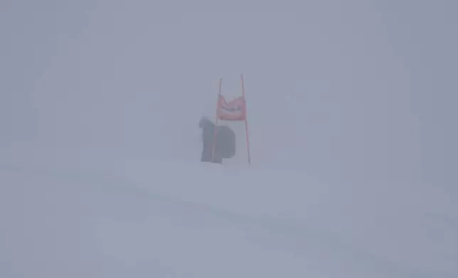 A gate is barely seen through the fog as an alpine ski, women's World Cup Super G race was canceled due to strong winds and poor visibility, in St. Moritz, Switzerland, Sunday, Dec. 22, 2024. (AP Photo/Marco Trovati)