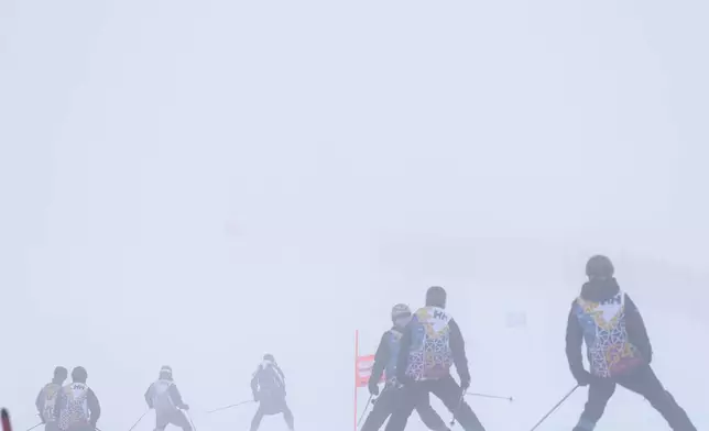 Race officials descend the course after an alpine ski, women's World Cup Super G race was canceled due to strong winds and poor visibility, in St. Moritz, Switzerland, Sunday, Dec. 22, 2024. (AP Photo/Marco Trovati)