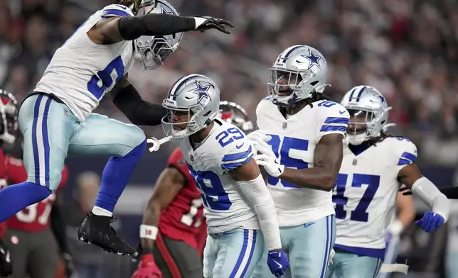 Dallas Cowboys' Buddy Johnson, left, and Andrew Booth Jr. (25) celebrate with C.J. Goodwin (29) after Goodwin made a stop on a punt coverage in the second half of an NFL football game against the Tampa Bay Buccaneers in Arlington, Texas, Sunday, Dec. 22, 2024. (AP Photo/Julio Cortez)