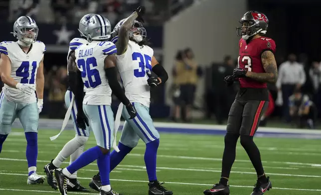 Dallas Cowboys' Marist Liufau (35), DaRon Bland (26), Nick Vigil (41) and others celebrate Liufau's defensive play as Tampa Bay Buccaneers' Mike Evans (13) looks on in the second half of an NFL football game in Arlington, Texas, Sunday, Dec. 22, 2024. (AP Photo/Jeffrey McWhorter)