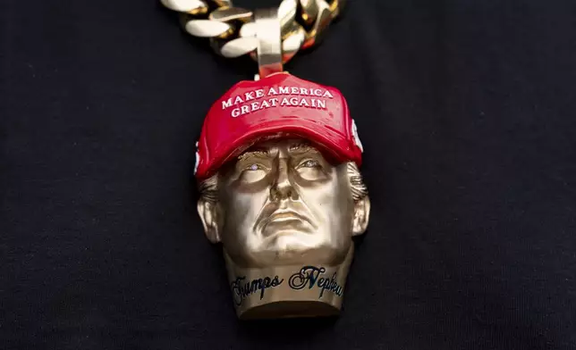 Forgiato Blow wears a necklace with a likeness of former President Donald Trump before Republican presidential nominee former President Donald Trump speaks at a campaign event at the Cobb Energy Performing Arts Centre, Tuesday, Oct. 15, 2024, in Atlanta. (AP Photo/Alex Brandon)