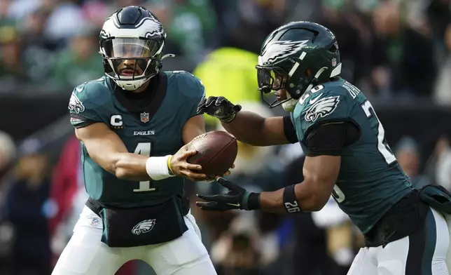 Philadelphia Eagles quarterback Jalen Hurts (1) hands off to Philadelphia Eagles running back Saquon Barkley (26) during the first half of an NFL football game against the Carolina Panthers on Sunday, Dec. 8, 2024, in Philadelphia. (AP Photo/Derik Hamilton)