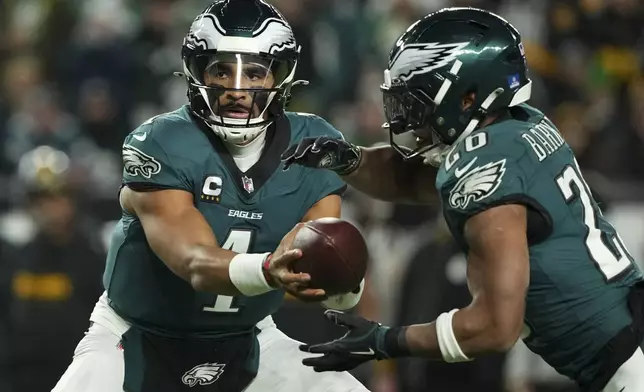 Philadelphia Eagles quarterback Jalen Hurts (1) hands off the ball to Philadelphia Eagles running back Saquon Barkley (26) during the first half of an NFL football game against the Pittsburgh Steelers on Sunday, Dec. 15, 2024, in Philadelphia. (AP Photo/Matt Slocum)