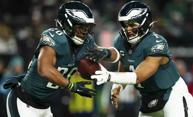 Philadelphia Eagles quarterback Jalen Hurts (1) hands off the ball to Philadelphia Eagles running back Saquon Barkley (26) during the first half of an NFL football game against the Pittsburgh Steelers on Sunday, Dec. 15, 2024, in Philadelphia. (AP Photo/Derik Hamilton)