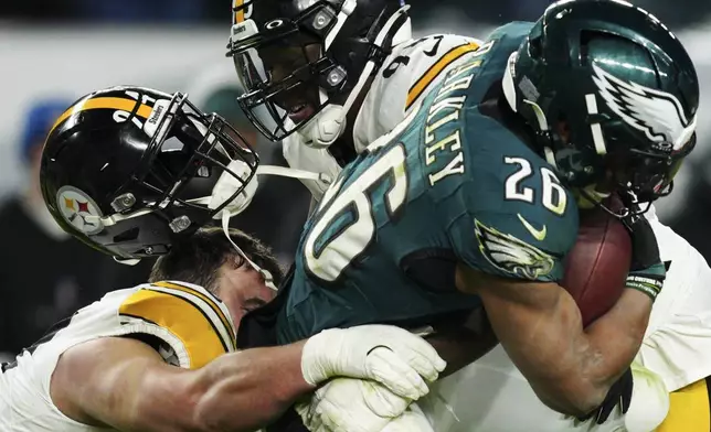 Philadelphia Eagles running back Saquon Barkley (26) is tackled by Pittsburgh Steelers defensive tackle Dean Lowry (94) as he loses his helmet during the second half of an NFL football game Sunday, Dec. 15, 2024, in Philadelphia. (AP Photo/Derik Hamilton)