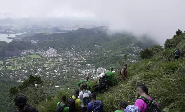 Volunteers with an organization that aims to increase accessibility in trails walk an inclusive route up Pedra da Gavea in Rio de Janeiro, Wednesday, Dec. 18, 2024. (AP Photo/Lucas Dumphreys)