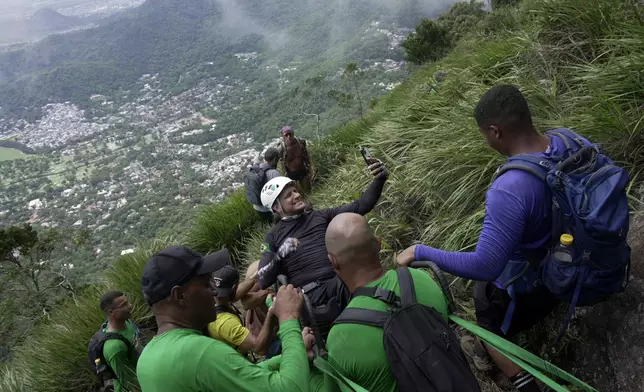 Ezequiel da Luz, a para-athlete with an amputated leg and no movement in his lower limbs, takes a selfie in a wheelchair as he is taken on an inclusive route up Pedra da Gavea with an organization that aims to increase accessibility in trails, in Rio de Janeiro, Wednesday, Dec. 18, 2024. (AP Photo/Lucas Dumphreys)