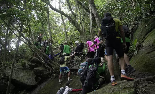 Volunteers with an organization that aims to increase accessibility in trails begin an inclusive walk up Pedra da Gavea, in Rio de Janeiro, Wednesday, Dec. 18, 2024. (AP Photo/Lucas Dumphreys)