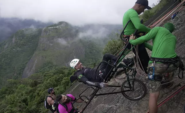 Ezequiel da Luz, a para-athlete with an amputated leg and no movement in his lower limbs, smiles in a wheelchair as he is taken on an inclusive route at Pedra da Gavea, with an organization that aims to increase accessibility in trails, in Rio de Janeiro, Wednesday, Dec. 18, 2024. (AP Photo/Lucas Dumphreys)