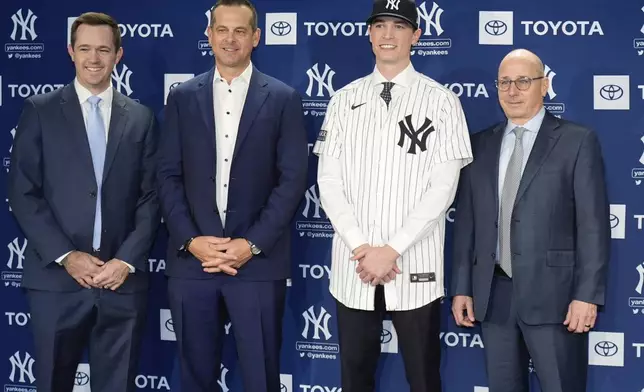 New York Yankees' Max Fried, second from right, poses with general manager Brian Cashman, right, manager Aaron Boone, second from left, and pitching coach Matt Blake, left, during a baseball news conference, Wednesday, Dec. 18, 2024, in New York. (AP Photo/Frank Franklin II)