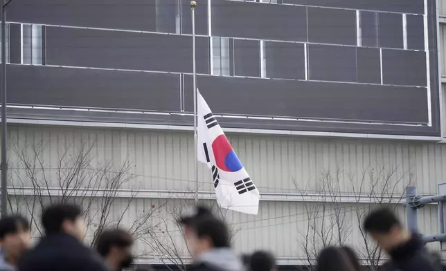 A South Korean national flag flies at half-staff in downtown Seoul, South Korea, Monday, Dec. 30, 2024, a day after a jetliner skidded off a runway, slammed into a concrete fence and burst into flames at an airport the town of Muan. (AP Photo/Lee Jin-man)