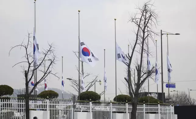 South Korean national flags fly at half-staff at a government complex in Seoul, South Korea, Monday, Dec. 30, 2024, a day after a jetliner skidded off a runway, slammed into a concrete fence and burst into flames at an airport the town of Muan. (AP Photo/Lee Jin-man)