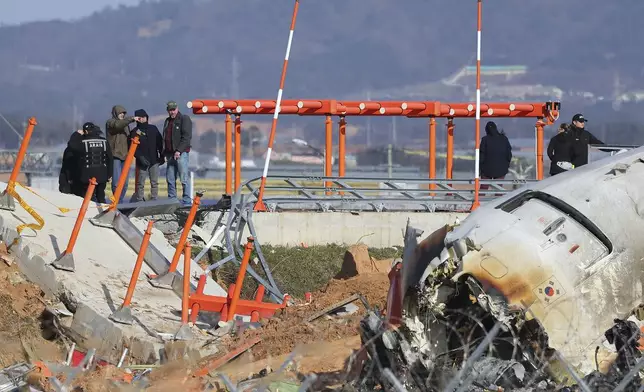 Experts from the U.S. National Transportation Safety Board (NTSB) and joint investigation team between the U.S. and South Korea check the site of a plane crash at Muan International Airport in Muan, South Korea, Tuesday, Dec. 31, 2024. (Son Hyung-joo/Yonhap via AP)