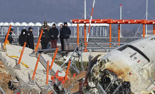 Experts from the U.S. National Transportation Safety Board (NTSB) and joint investigation team between the U.S. and South Korea check the site of a plane crash at Muan International Airport in Muan, South Korea, Tuesday, Dec. 31, 2024. (Son Hyung-joo/Yonhap via AP)