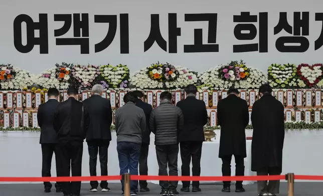 Mourners pray for the victims of a plane fire at a memorial altar at Muan sport park in Muan, South Korea, Monday, Dec. 30, 2024. The sign reads "The victims on a plane." (AP Photo/Ahn Young-joon)