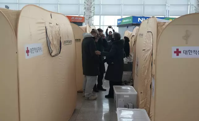 Relatives of the passengers of a plane which burst into flames, react at a temporary shelter at Muan International Airport in Muan, South Korea, Monday, Dec. 30, 2024. (AP Photo/Ahn Young-joon)