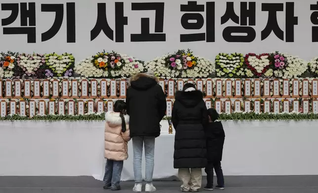 Mourners pray for the victims on a plane fire at a memorial altar at Muan sport park in Muan, South Korea, Monday, Dec. 30, 2024. The sign reads "The victims on a plane." (AP Photo/Ahn Young-joon)