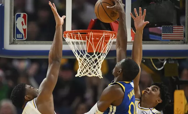 Golden State Warriors forward Jonathan Kuminga (00) dunks against Los Angeles Lakers forward Rui Hachimura, left, and guard Max Christie, right, during the first half of an NBA basketball game Wednesday, Dec. 25, 2024, in San Francisco. (AP Photo/Eakin Howard)