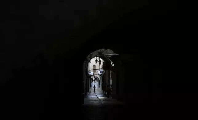 Pedestrians walk through an alley of Jerusalem's Old City, Tuesday, Dec. 3, 2024. (AP Photo/Matias Delacroix)