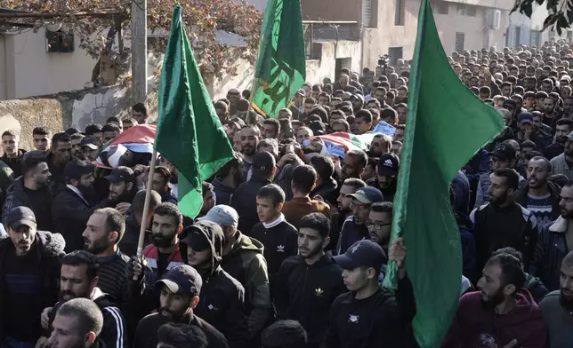 Mourners carry Hamas flags and the bodies, wrapped with the Palestinian flag, of Akram Abu Arrah and Mohammad Ghannam, both killed in an airstrike Israel said targeted a militant cell, during their funeral in the West Bank village of Al-Aqaba, Tuesday Dec. 3, 2024. (AP Photo/Majdi Muhammad)