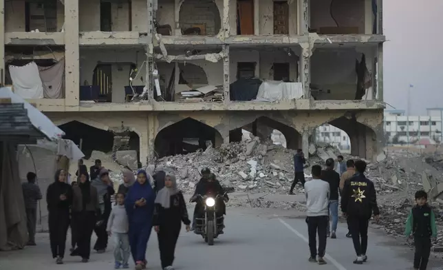 Palestinian walk past destroyed building at a neighbourhood in Khan Younis, Gaza Strip, Sunday, Dec. 1, 2024. (AP Photo/Abdel Kareem Hana)