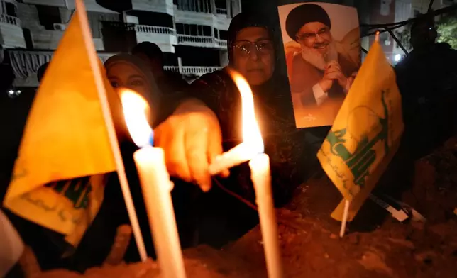 A woman lights candles at the site where former Hezbollah leader Sayyed Hassan Nasrallah was killed by Israeli airstrikes late September during a memorial ceremony in Dahiyeh, in the southern suburb of Beirut, Lebanon, Saturday, Nov. 30, 2024. (AP Photo/Hussein Malla)