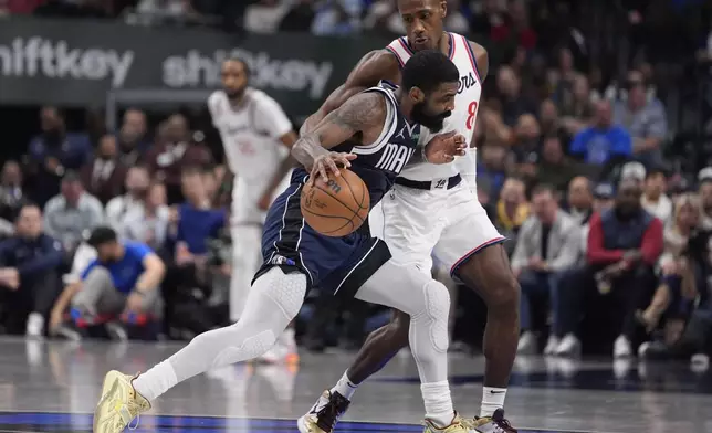 Dallas Mavericks guard Kyrie Irving (11) drives against Los Angeles Clippers guard Kris Dunn (8) during the first half of an NBA basketball game, Saturday, Dec. 21, 2024, in Dallas. (AP Photo/LM Otero)