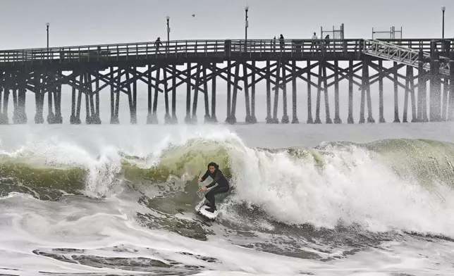 A surfer rides a wave at Seal Beach, Calif., Monday, Dec. 23, 2024. (Jeff Gritchen/The Orange County Register via AP)