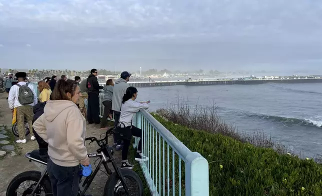 Spectators look out at a closed Santa Cruz wharf after the pier partially collapsed and fell into the ocean on Monday, Dec. 23, 2024, in Santa Cruz, Calif. (AP Photo/Martha Mendoza)