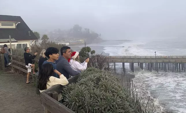 Spectators watch high surf roll in near the Capitola Wharf, Monday, Dec. 23, 2024, in Capitola, Calif. (AP Photo/Pamela Hassell)