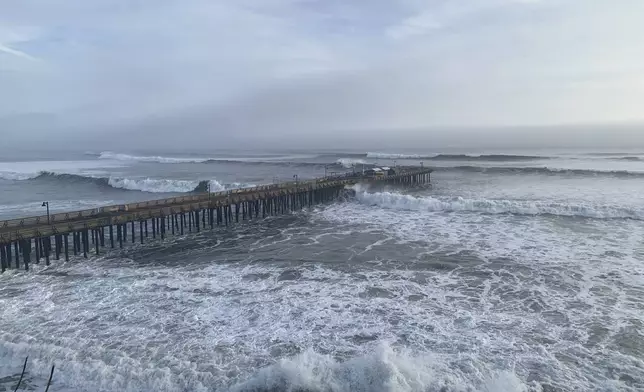 High surf rolls past the Capitola Wharf, Monday, Dec. 23, 2024, in Capitola, Calif. (AP Photo/Pamela Hassell)