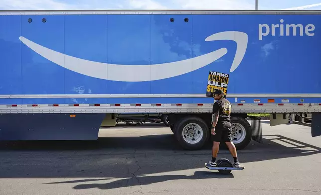 UPS driver Jhon Solidum, a member of the Teamsters union, rides a one wheeler to support the Amazon workers striking outside an Amazon Fulfillment Center as Teamsters seek labor contract nationwide, Thursday, Dec. 19, 2024, in City of Industry, Calif. (AP Photo/Damian Dovarganes)