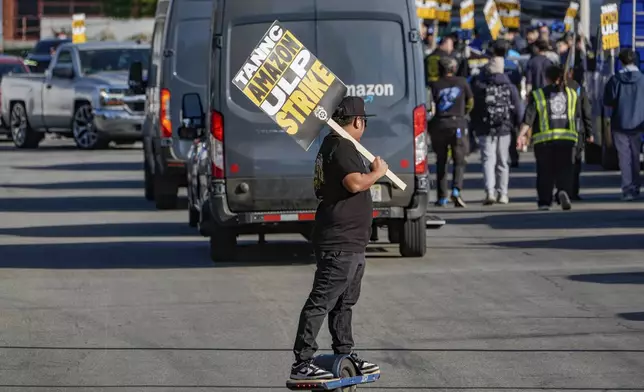 UPS driver Jhon Solidum, a member of the Teamsters union, rides a one wheeler to support the Amazon workers striking outside an Amazon Fulfillment Center as Teamsters seek labor contract nationwide, Thursday, Dec. 19, 2024, in City of Industry, Calif. (AP Photo/Damian Dovarganes)