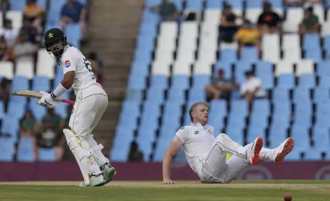 Pakistan's Aamer Jamal, left, makes a run whilst South Africa's Corbin Bosch falls to the ground during day three of the Test cricket match between South Africa and Pakistan, at the Centurion Park in Centurion, South Africa, Saturday, Dec. 28, 2024. (AP Photo/Themba Hadebe)