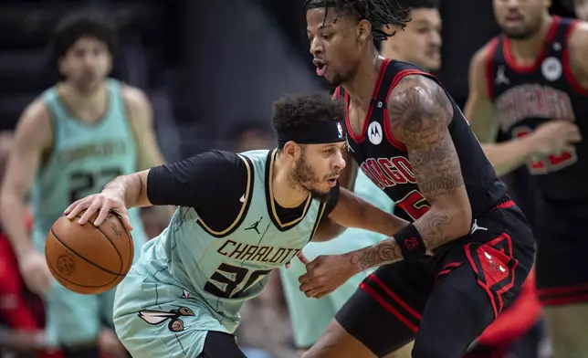 Chicago Bulls forward Dalen Terry, front right, defends against Charlotte Hornets guard Seth Curry, left, during the first half of an NBA basketball game in Charlotte, N.C., Monday, Dec. 30, 2024. (AP Photo/Jacob Kupferman)