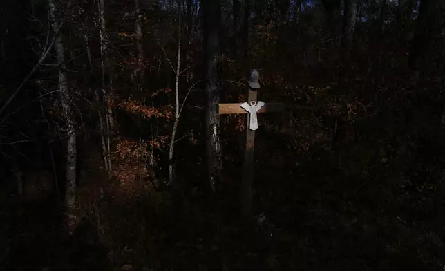 A cross marks the location along Elder Road, Thursday, Dec. 5, 2024, in Dadeville, Ala, where the Alexander City Community Work Center transport van crashed in April 2024, killing Willie Crayton and Bruce Clements. The Lord's Prayer is written on the angel on the cross and hat atop it, belonged to Crayton. (AP Photo/Carolyn Kaster)