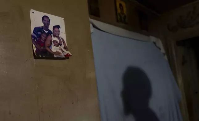 Tyrone Heard, shadow at right, looks at a photo of himself with his family pinned to the wall of his home, Friday, Dec. 6, 2024, in Alexander City, Ala. (AP Photo/Carolyn Kaster)