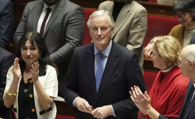 French Prime Minister Michel Barnier gets applause from ministers after addressing the National Assembly prior to a vote on a no-confidence motion that could bring him down and his cabinet for the first time since 1962, Wednesday, Dec. 4, 2024 in Paris. (AP Photo/Michel Euler)