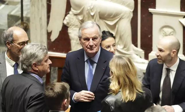 French Prime Minister Michel Barnier, center, talks to people at the National Assembly before French lawmakers vote on a no-confidence motion that could bring down the prime minister and the government for the first time since 1962, Wednesday, Dec. 4, 2024 in Paris. (AP Photo/Michel Euler)