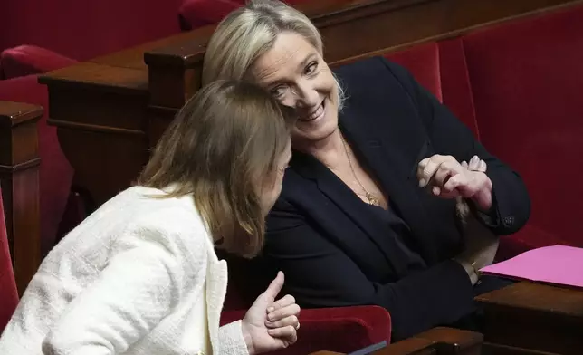 French far-right leader Marine Le Pen, right, talks with a National Rally parliament member at the National Assembly before French lawmakers vote on a no-confidence motion that could bring down the Prime Minister and the government for the first time since 1962, Wednesday, Dec. 4, 2024 in Paris. (AP Photo/Michel Euler)