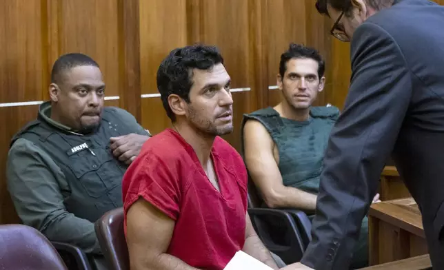 Oren Alexander, 37, center, and his twin brother, Alon, center-right, speak to their attorney Joel Denaro during their bond hearing after being charged with multiple state and federal crimes, including sex trafficking and rape, at the Richard E. Gerstein Justice Building on Friday, Dec. 13, 2024, in Miami. (Matias J. Ocner/Miami Herald via AP, Pool)