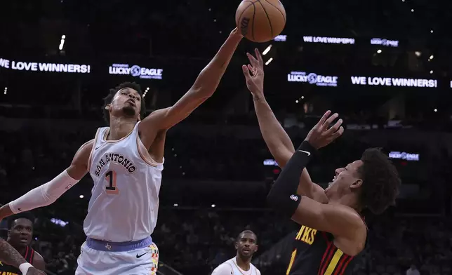 San Antonio Spurs center Victor Wembanyama (1) swats at a shot attempt by Atlanta Hawks forward Jalen Johnson, right, during the first half of an NBA basketball game in San Antonio, Thursday, Dec. 19, 2024. (AP Photo/Kin Man Hui)