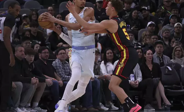 Atlanta Hawks guard Dyson Daniels (5) puts pressure on San Antonio Spurs center Victor Wembanyama, left, during the first half of an NBA basketball game in San Antonio, Thursday, Dec. 19, 2024. (AP Photo/Kin Man Hui)