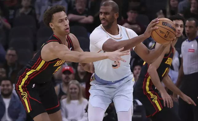 San Antonio Spurs guard Chris Paul, right, gets pressure from Atlanta Hawks guard Dyson Daniels, left, during the first half of an NBA basketball game in San Antonio, Thursday, Dec. 19, 2024. (AP Photo/Kin Man Hui)