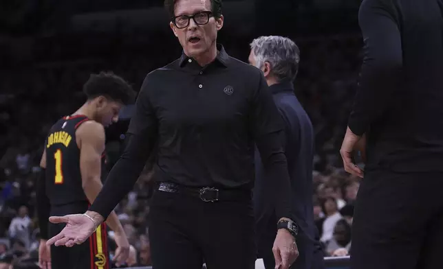 Atlanta Hawks head coach Quin Snyder, center, converses with a game official after a play during the first half of an NBA basketball game in San Antonio, Thursday, Dec. 19, 2024. (AP Photo/Kin Man Hui)