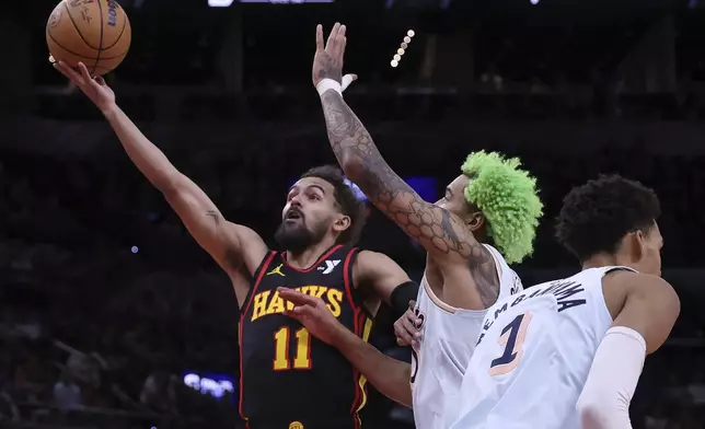 Atlanta Hawks guard Trae Young (11) goes for a shot against San Antonio Spurs forward Jeremy Sochan, right, during the first half of an NBA basketball game in San Antonio, Thursday, Dec. 19, 2024. (AP Photo/Kin Man Hui)