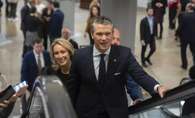 Pete Hegseth, President-elect Donald Trump's nominee to be defense secretary, is joined by his wife Jennifer Rauchet, as they walk through the basement of the Capitol, Wednesday, Dec. 4, 2024, in Washington. (AP Photo/Mark Schiefelbein)