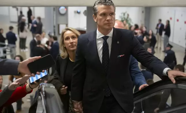 Pete Hegseth, President-elect Donald Trump's nominee to be defense secretary, is joined by his wife Jennifer Rauchet, as they walk through the basement of the Capitol, Wednesday, Dec. 4, 2024, in Washington. (AP Photo/Mark Schiefelbein)