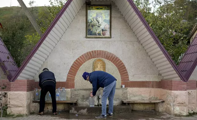 FILE - Men collect water from a fountain in the village of Hrusevo, Moldova, Sunday, Oct. 20, 2024. (AP Photo/Vadim Ghirda, File)